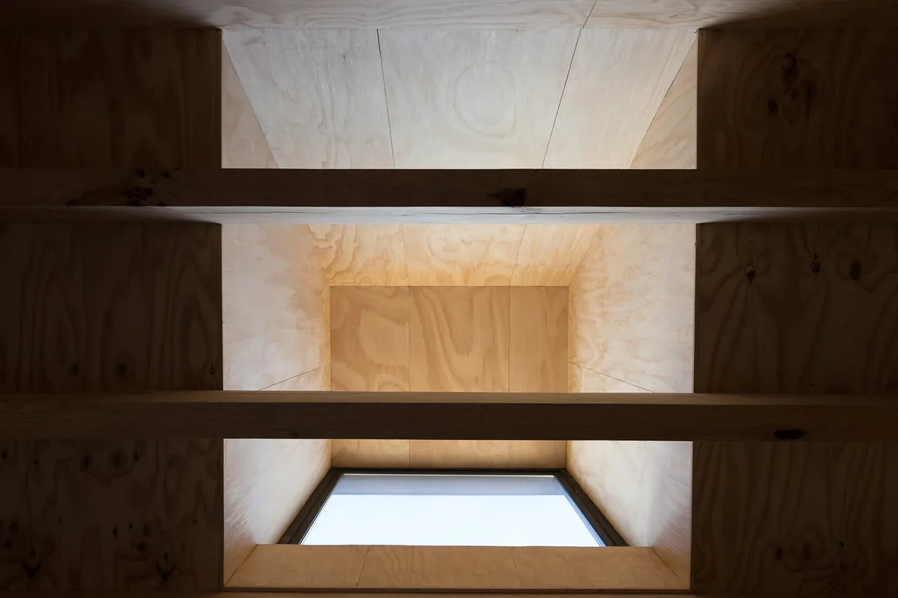 A wooden stairwell shaft illuminated from a rectangular window at the bottom end.