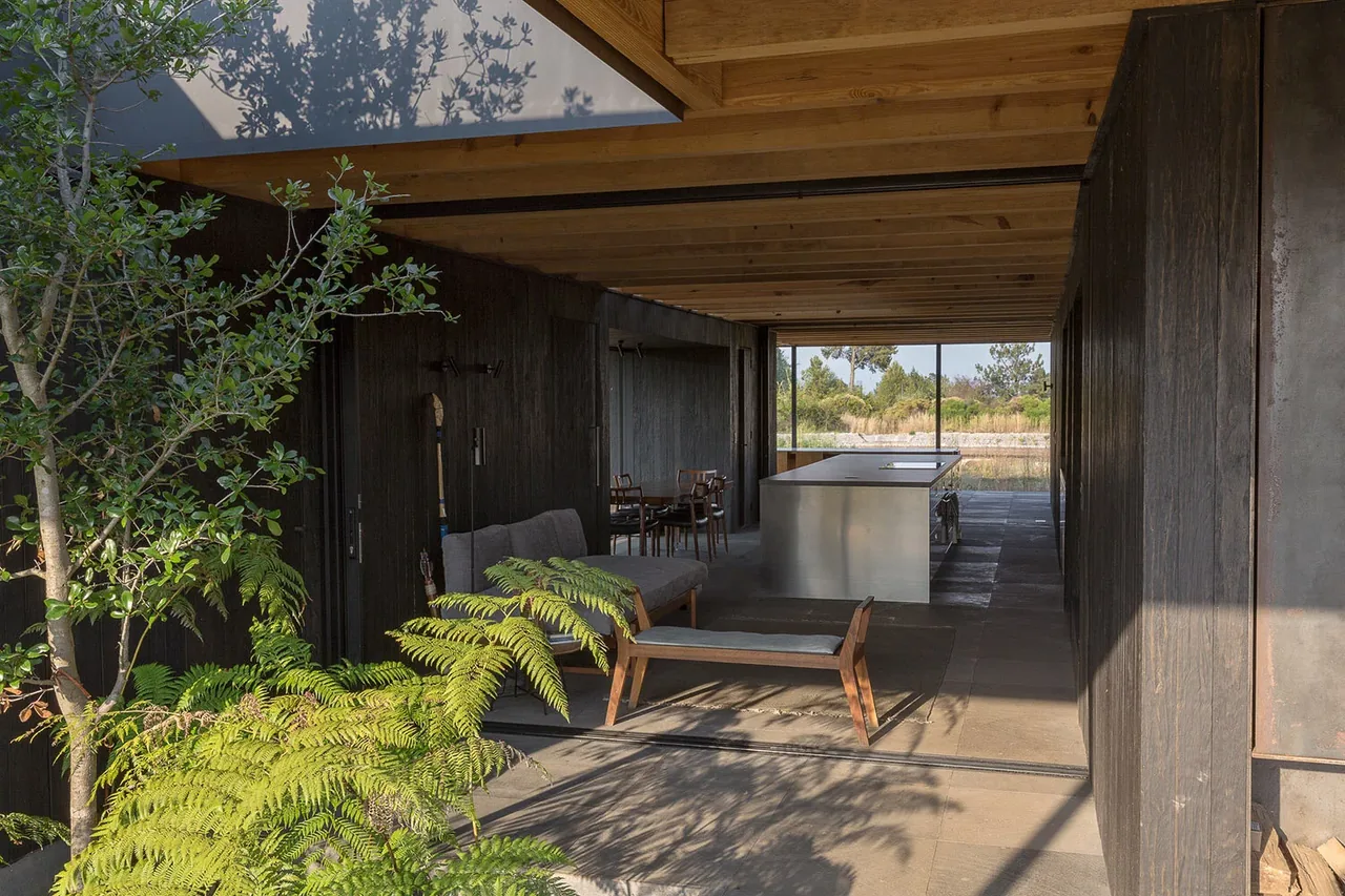 Casa Temascaltepec features an outdoor living area with a wooden ceiling, metal kitchen island, and seating that overlooks a natural landscape.