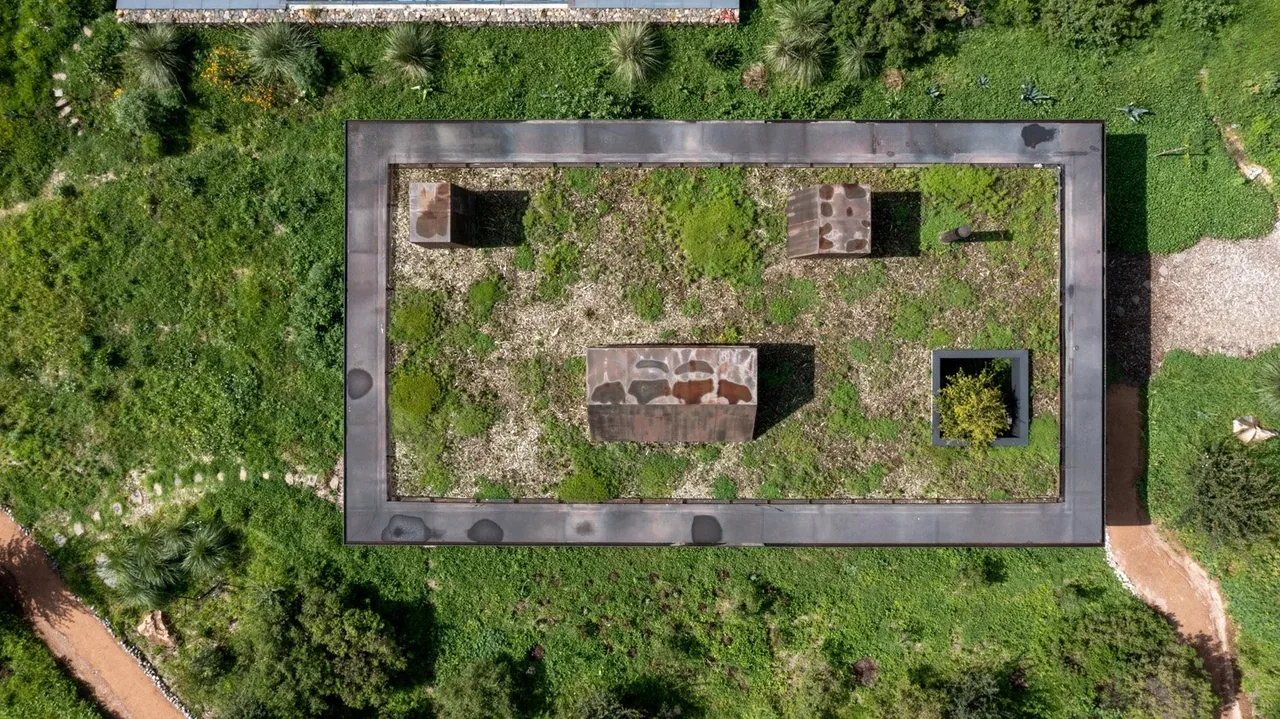 Casa Temascaltepec features a flat green roof with integrated vegetation and metal elements, blending into the natural landscape.
