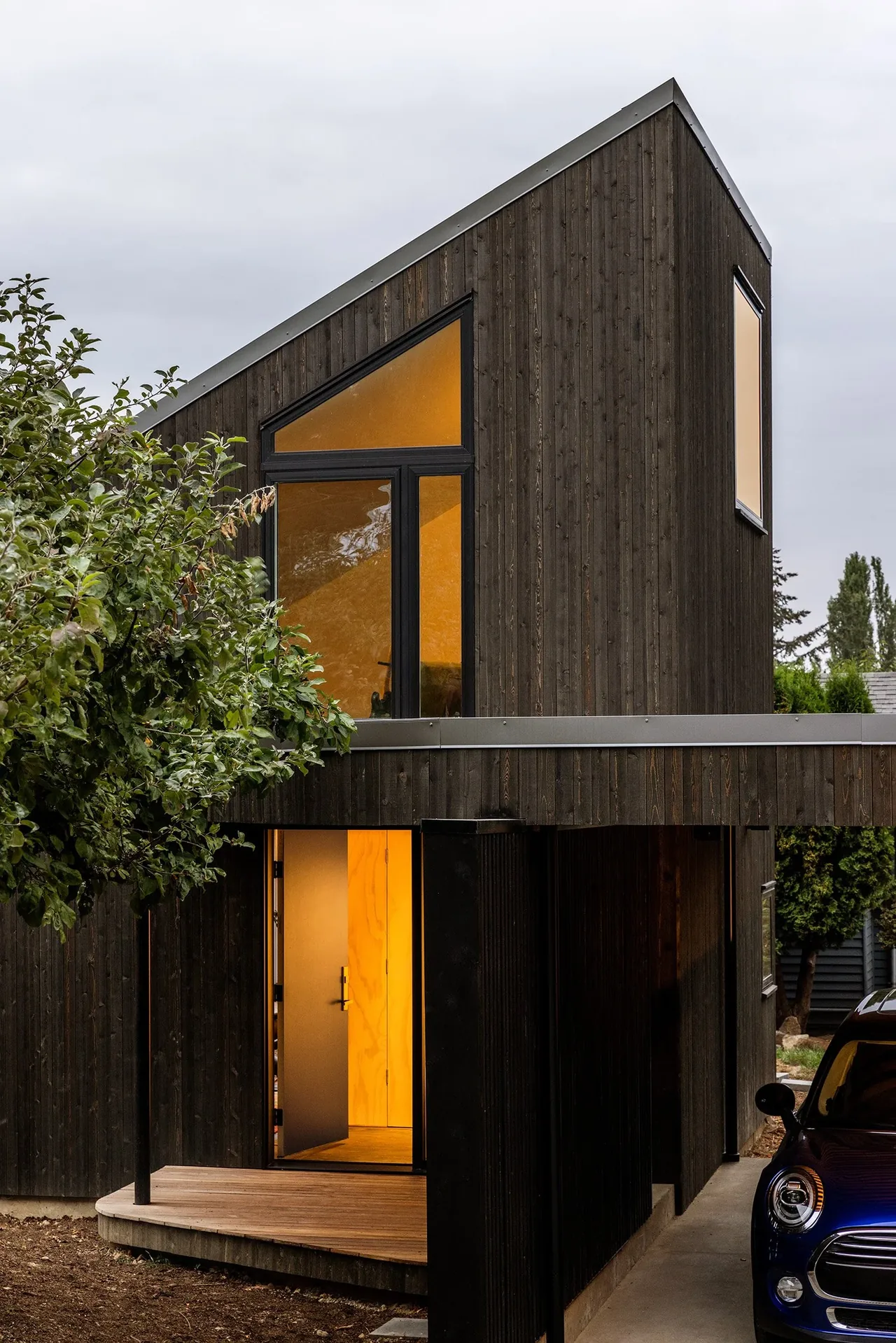 House O features dark vertical wood siding with prominent triangular windows and a wood deck entry.