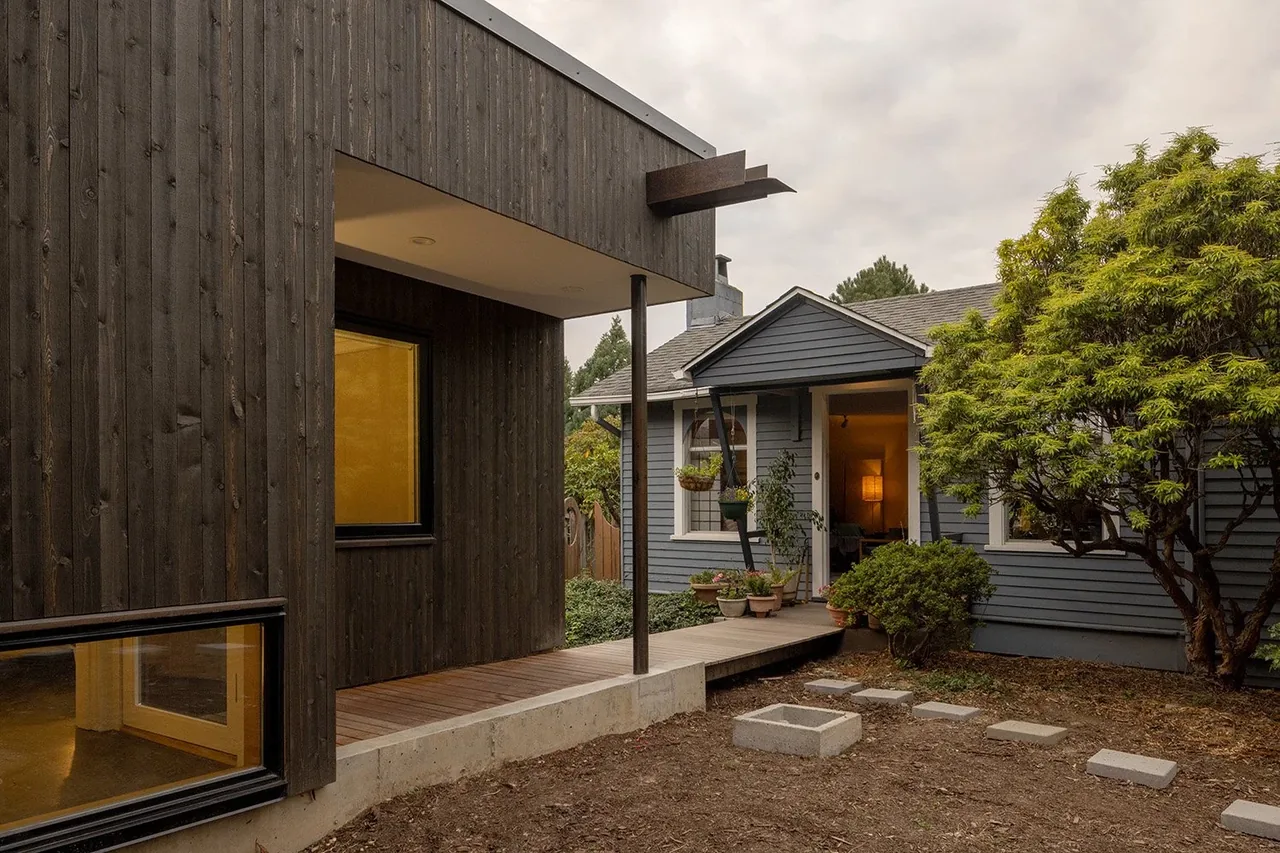 Modern black wood siding contrasts with traditional blue siding in this residential addition by Hutchison & Maul Architecture in Seattle.