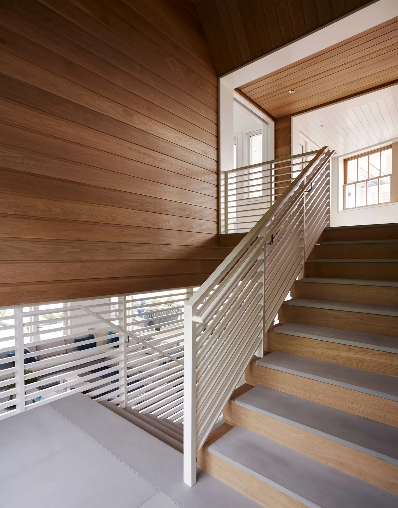 Modern interior stair with wood panel walls and white horizontal metal railing.