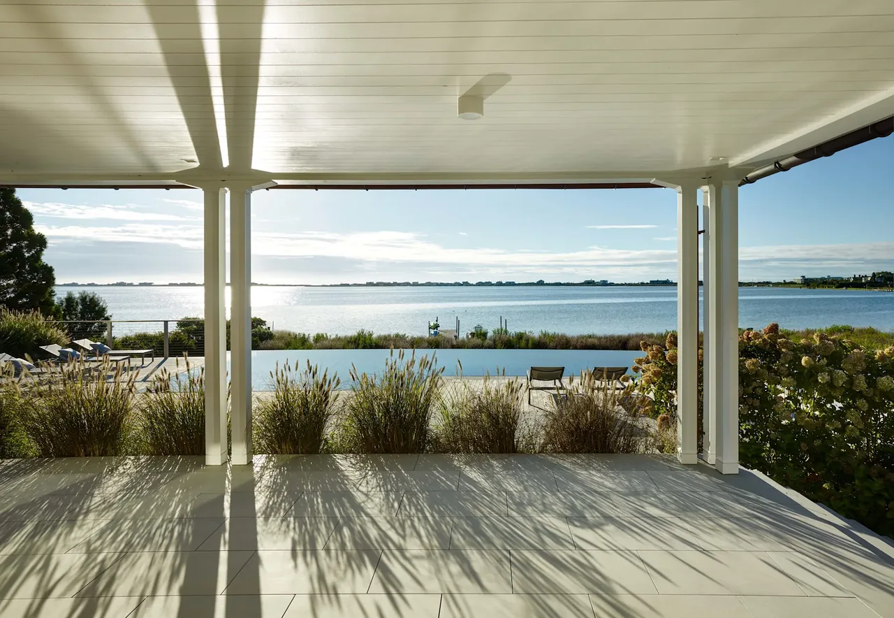 Covered patio at Water Mill House with views of the infinity pool and water beyond.