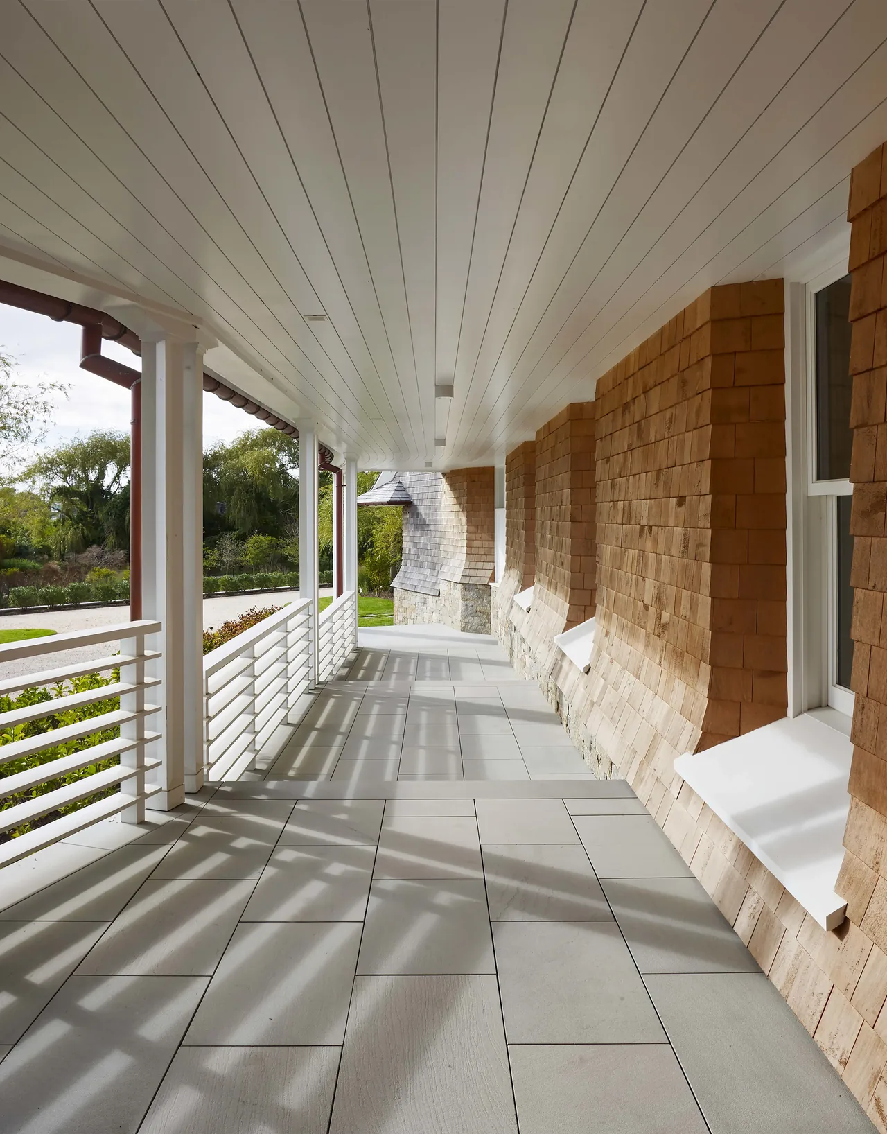 The Water Mill House features a covered porch with natural wood shingle siding and tiled flooring.