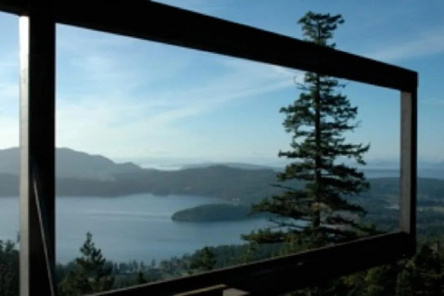 The photo captures the scenic view of a lake and surrounding hills through a wood-framed window opening.