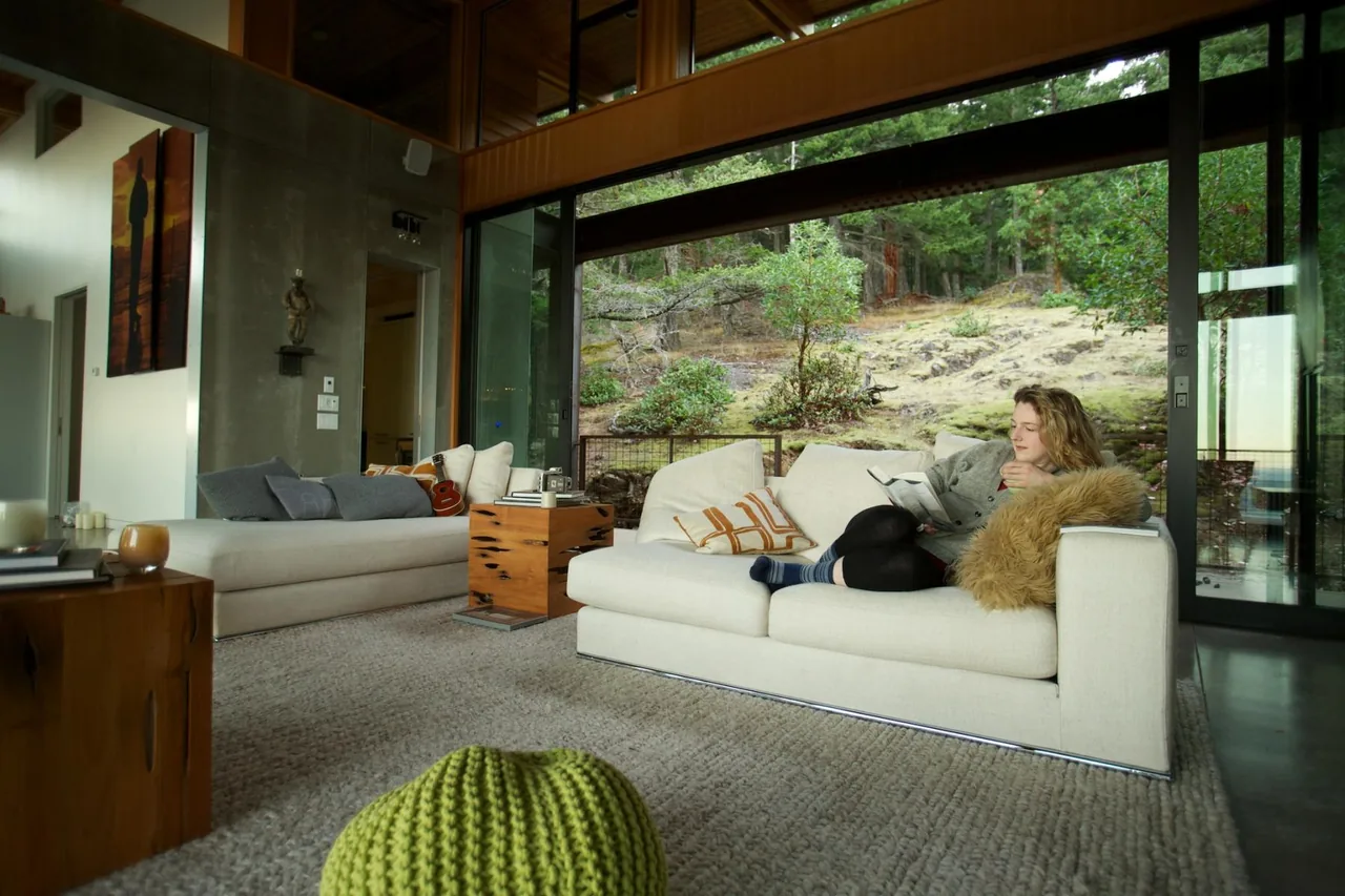 Living room with floor-to-ceiling sliding glass doors reveals a natural hillside view beyond the seating area.