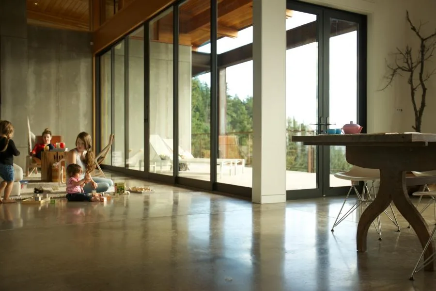 Spacious interior with polished concrete floor and floor-to-ceiling sliding glass doors opening to an outdoor deck area.