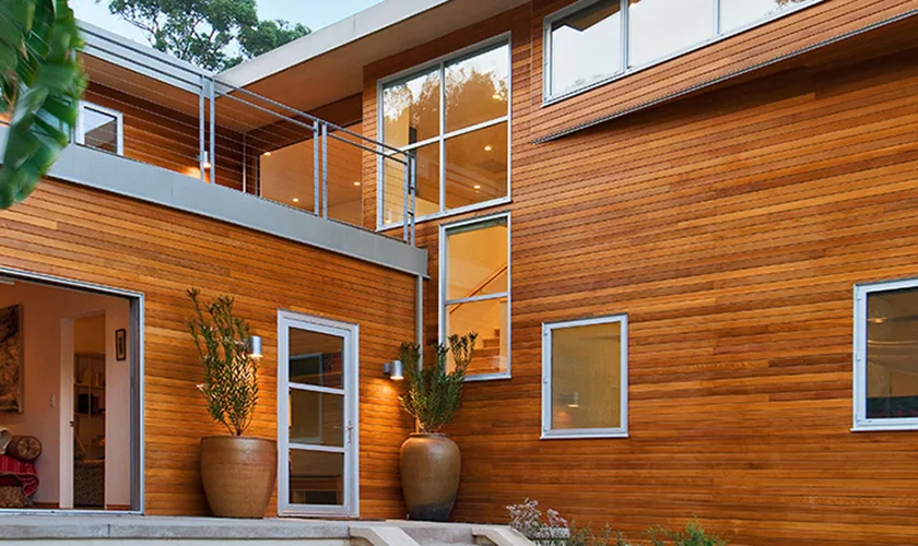 Modern exterior with horizontal wood siding and metal cable railing above a patio door.