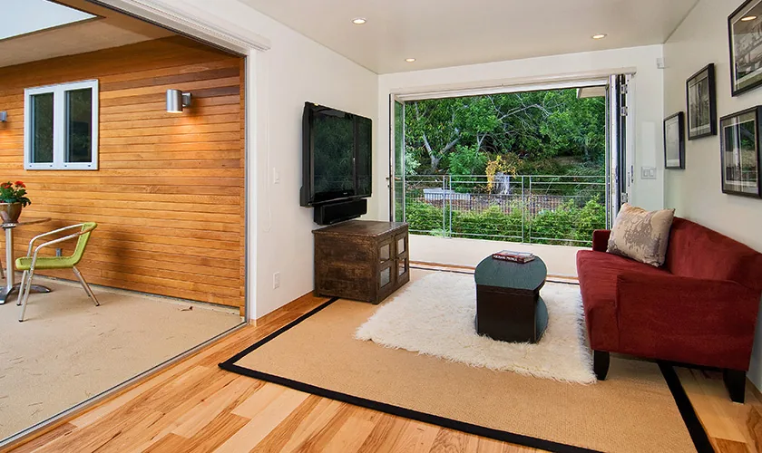 Living room with folding glass doors opens to a covered patio with wood siding exterior.