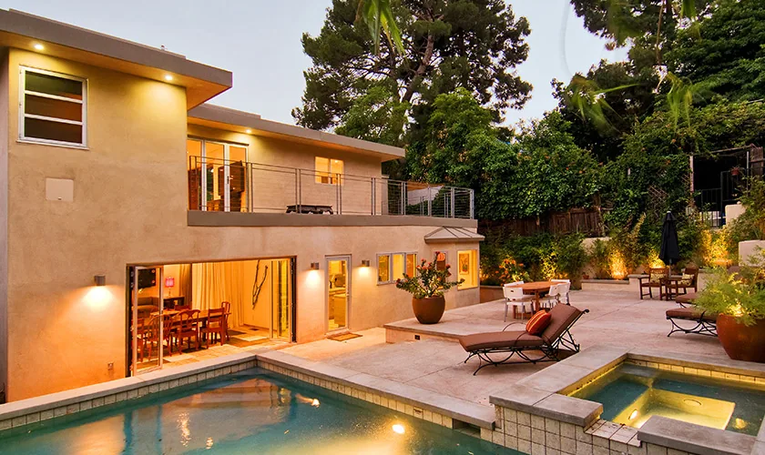 The RIDPATH project features a stucco exterior home with a pool and illuminated outdoor patio area at dusk.