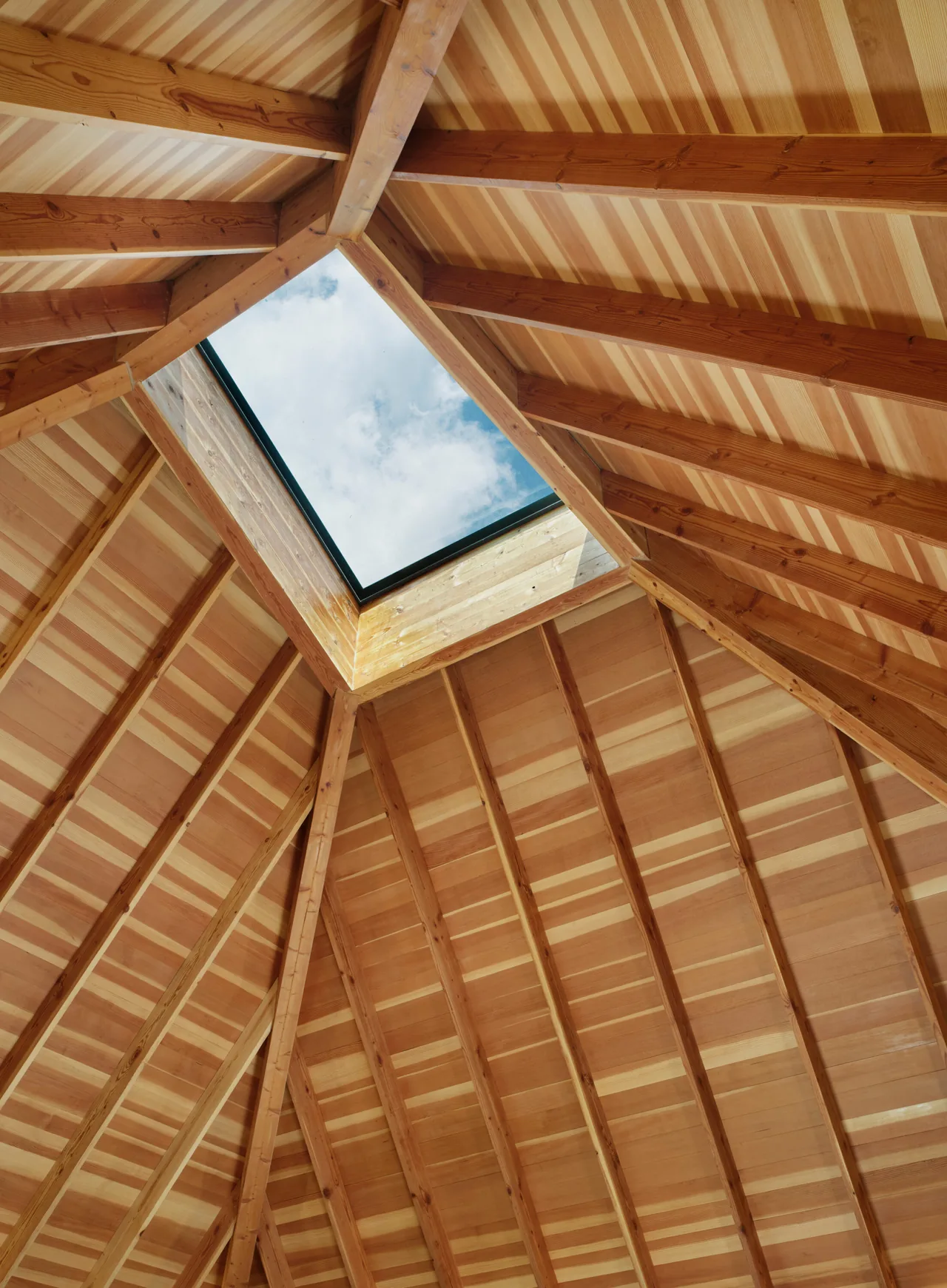 Vaulted wooden ceiling with exposed beams and a skylight at River Bend Residence by Lake | Flato Architects.