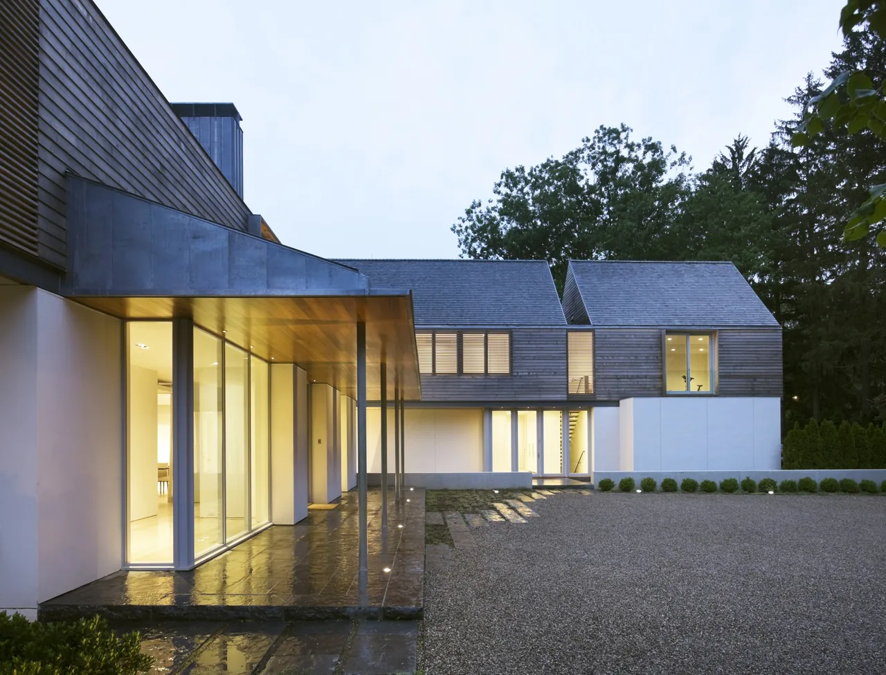 Exterior front view of modern home '44PL' by Joeb + Partners, featuring wood siding and large windows.