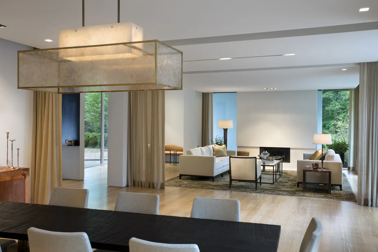 Open living area with beige sofas, area rug, and a large rectangular pendant light over the dining table.