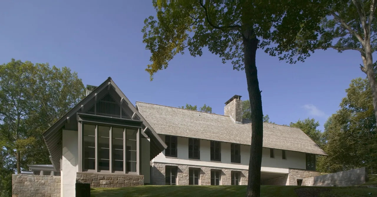 Riverbank Residence features a steep roof pitch and stone retaining walls, visible from the exterior view.