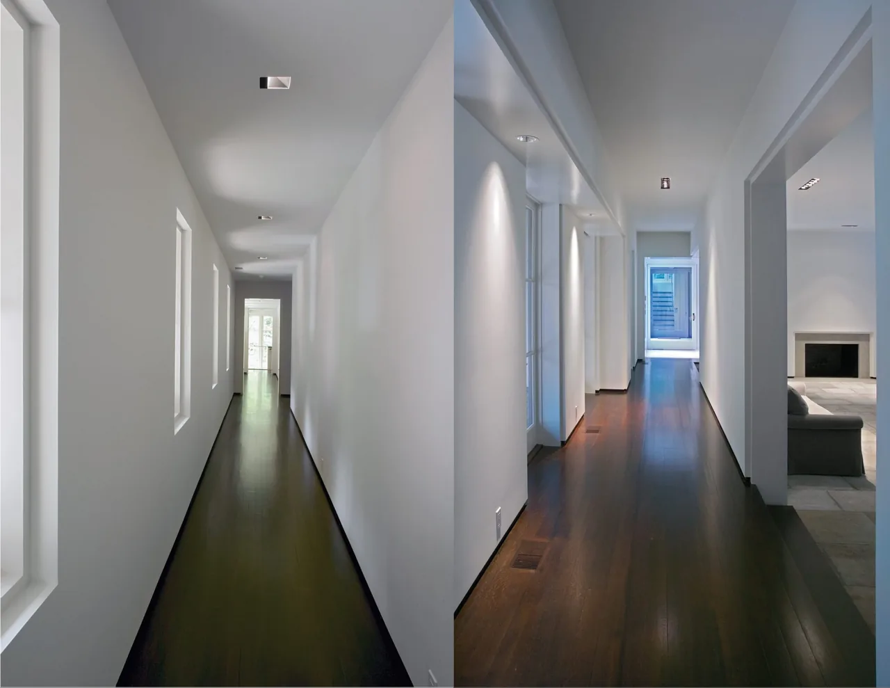 Minimalist hallway with dark wood floor and recessed lighting leads to a door at the end, adjoining a living room with a fireplace.