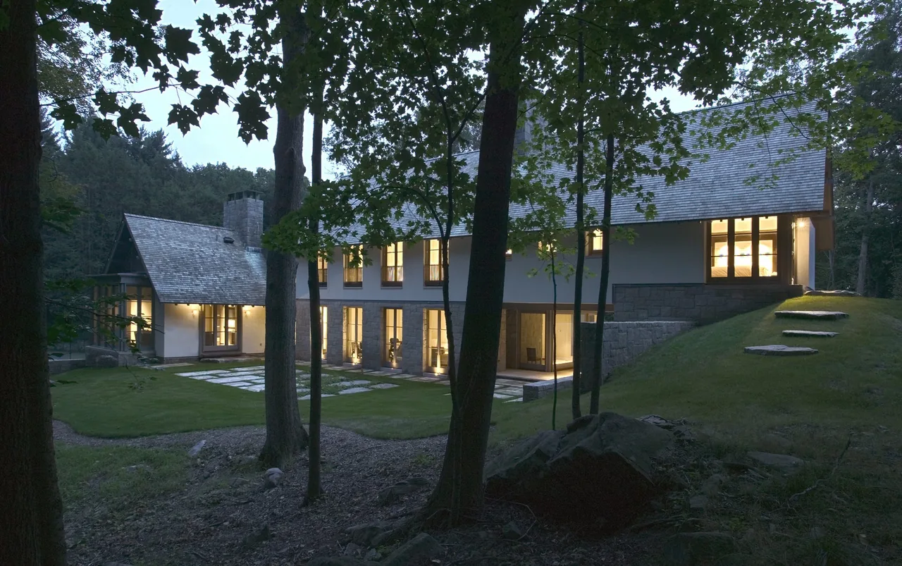 The Riverbank Residence features a traditional style with gable roofs and a stone foundation visible.
