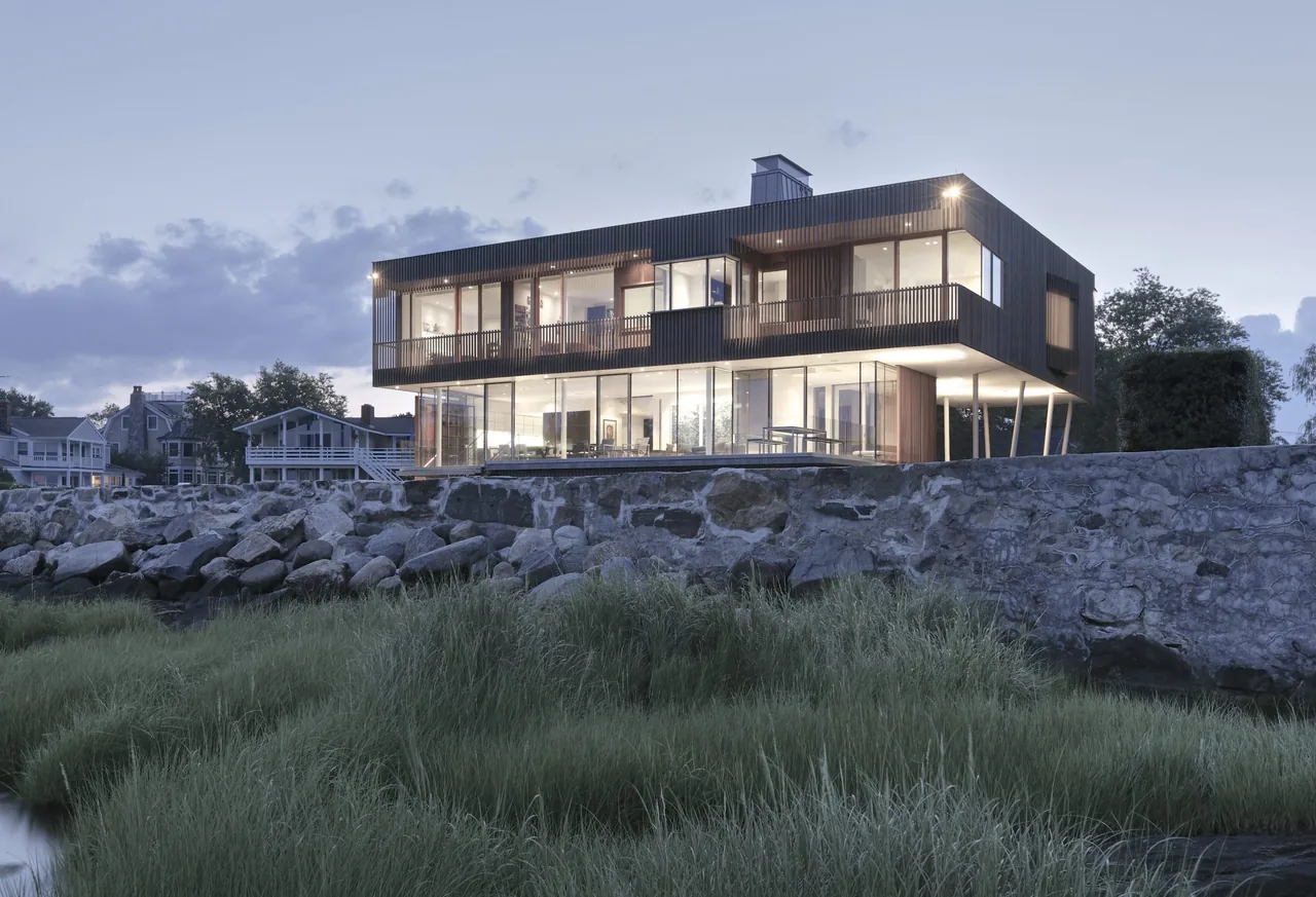 The Spiral House by Joeb + Partners Architects features vertical wood slat siding and an elevated structure over a rocky foundation.