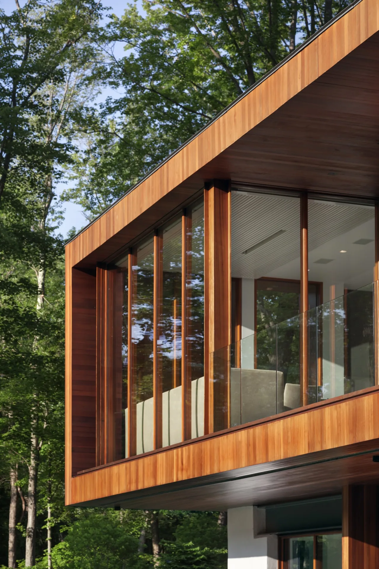 Cantilevered balcony with wood cladding and floor-to-ceiling wood-framed glazing in a modern house.