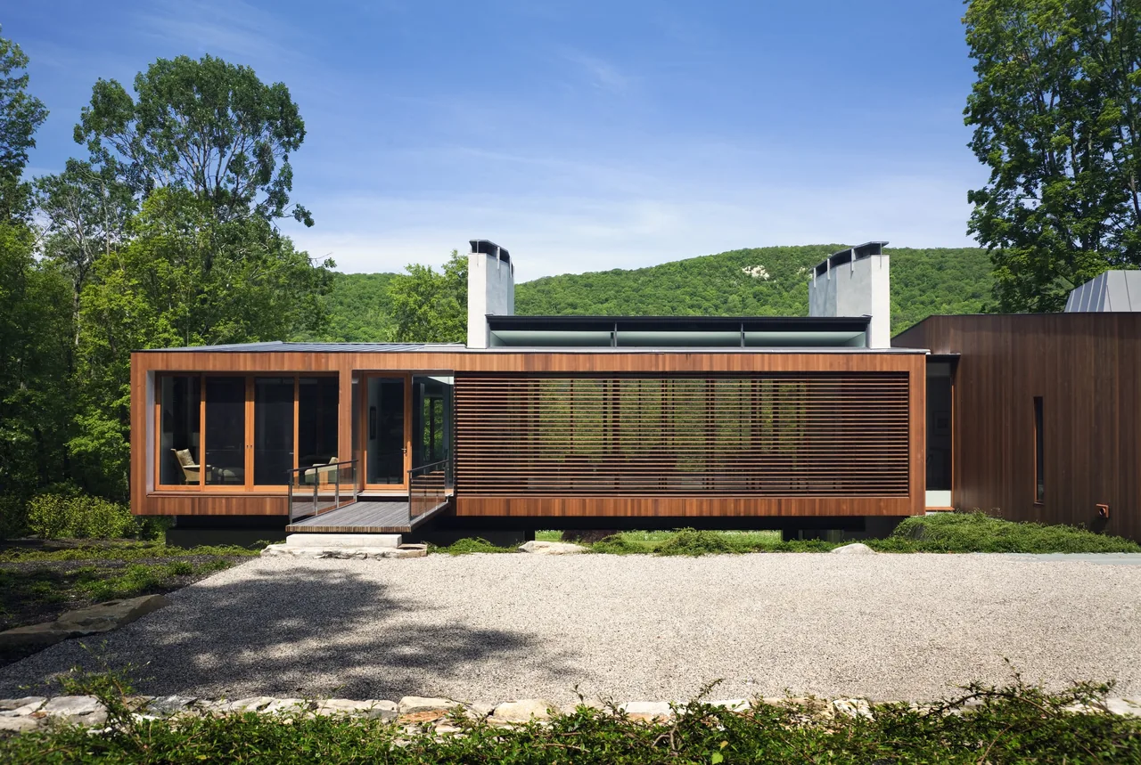 Bridge House features a horizontal wood-slat facade overlooking a natural landscape with mountain views.