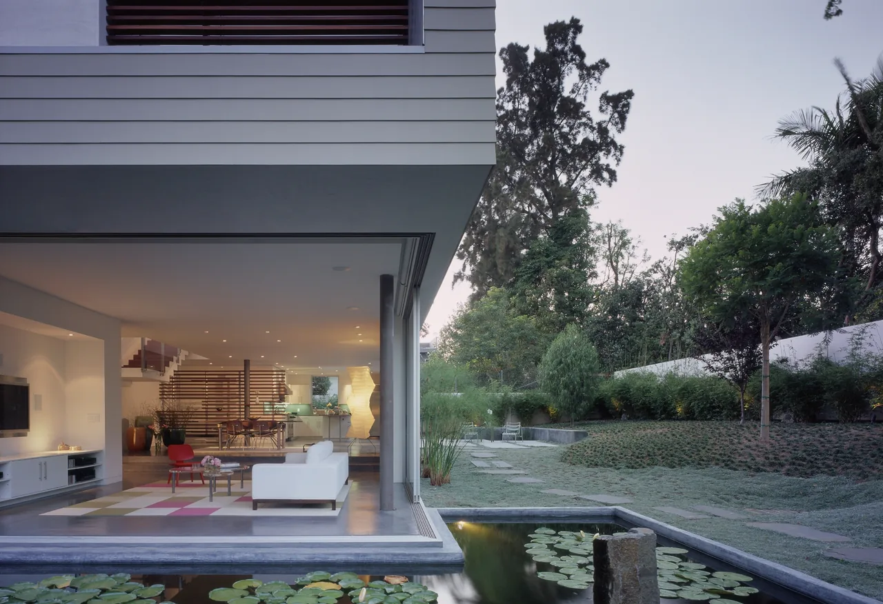 The Ehrlich House features an open living area that seamlessly connects to a garden with a lily pond, designed by John Friedman Alice Kimm Architects.