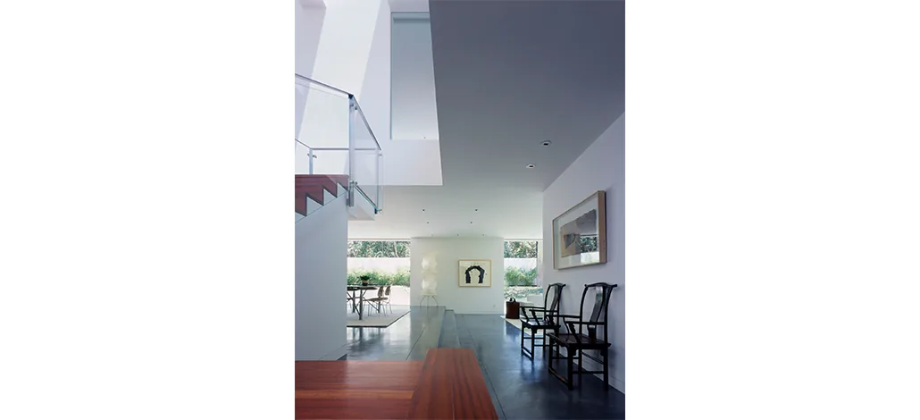 Ehrlich House features an open living space with a floating staircase and large windows for garden views.