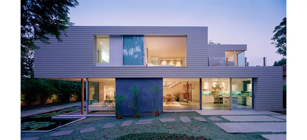 Ehrlich House by John Friedman Alice Kimm Architects features horizontal wood siding and floor-to-ceiling glazing with views of a lily pond.