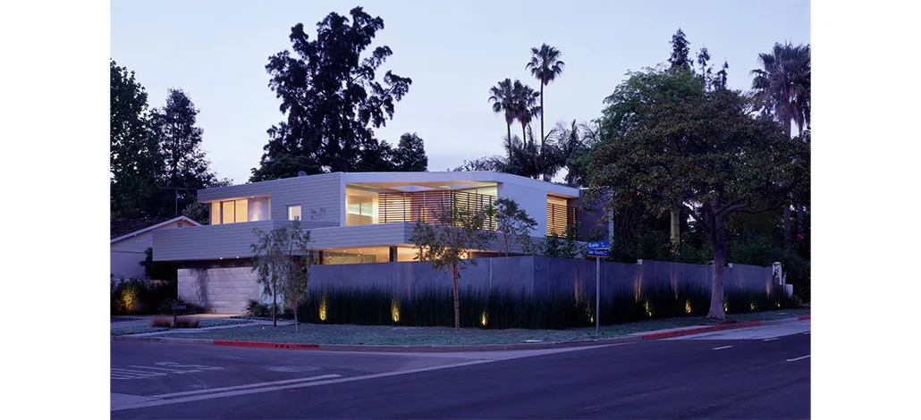 Ehrlich House shows modern two-story design with horizontal siding and illuminated garden landscape at night.