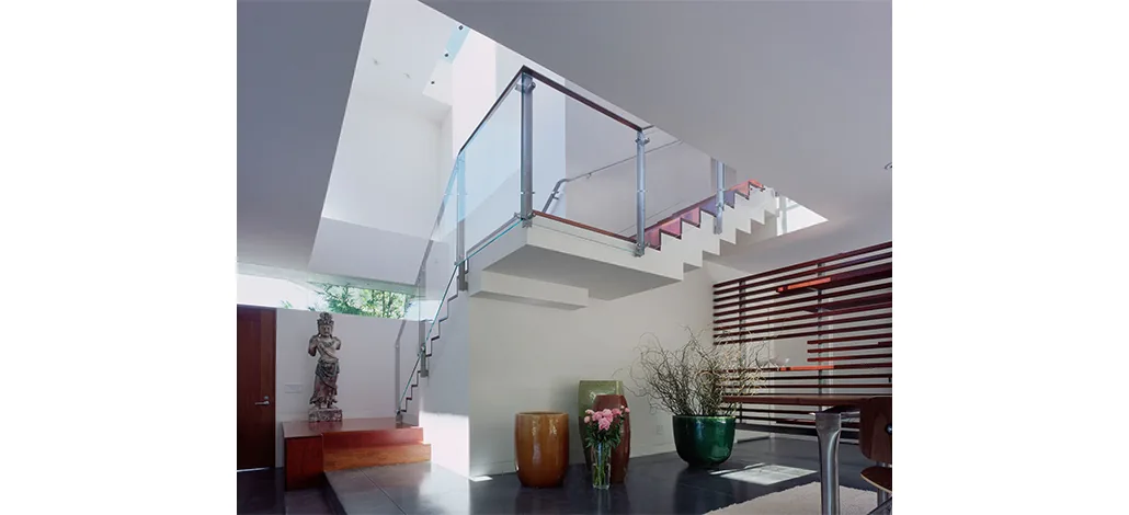 The Ehrlich House features a stair landing with glass and metal railings illuminated by a skylight overhead.