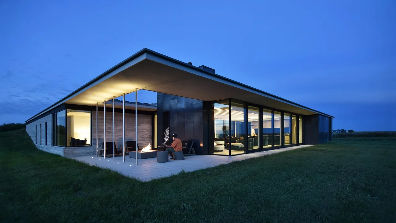 Spoonbill Ranch features floor-to-ceiling glazing and a covered patio with a fire pit, designed by Johnsen Schmaling Architects.