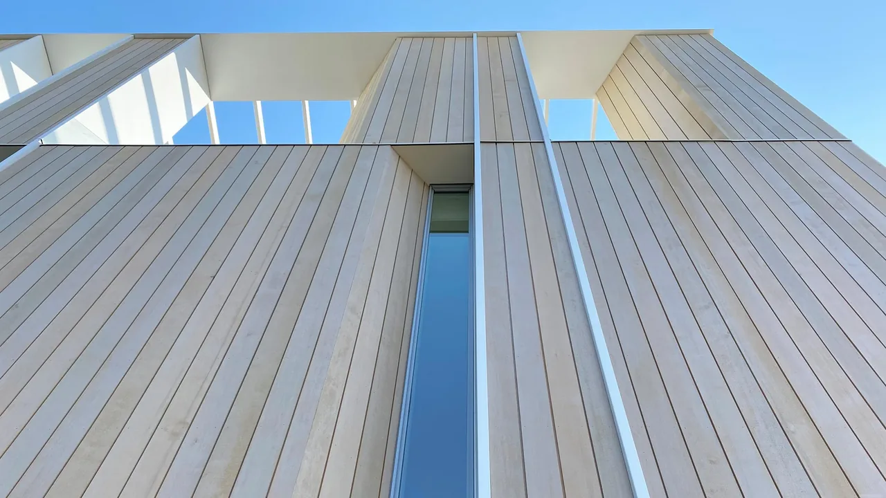Vertical wood panels on the facade with narrow vertical windows and a glass roof pergola above.