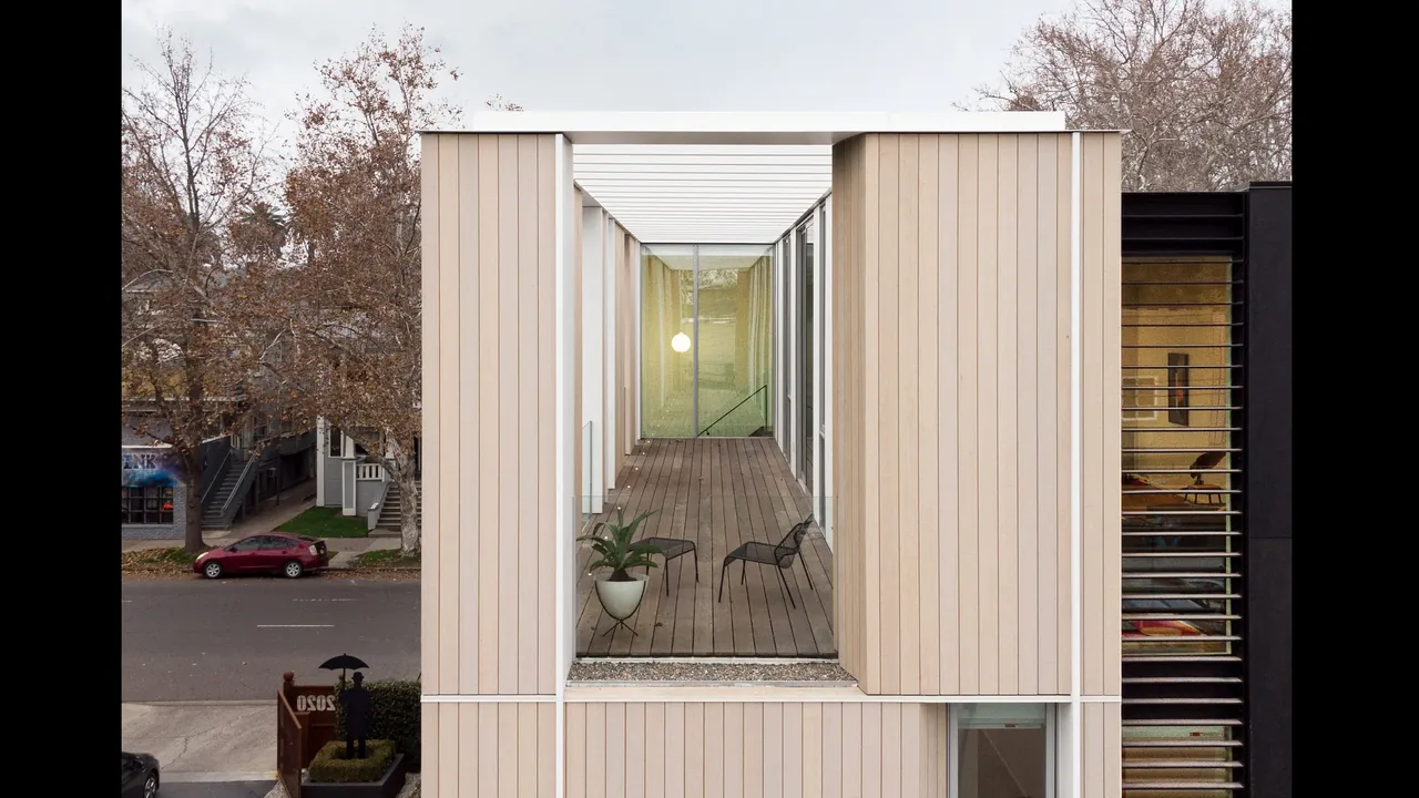 The Flex House features vertical wood siding and a wood-floored balcony with a glass roof pergola.
