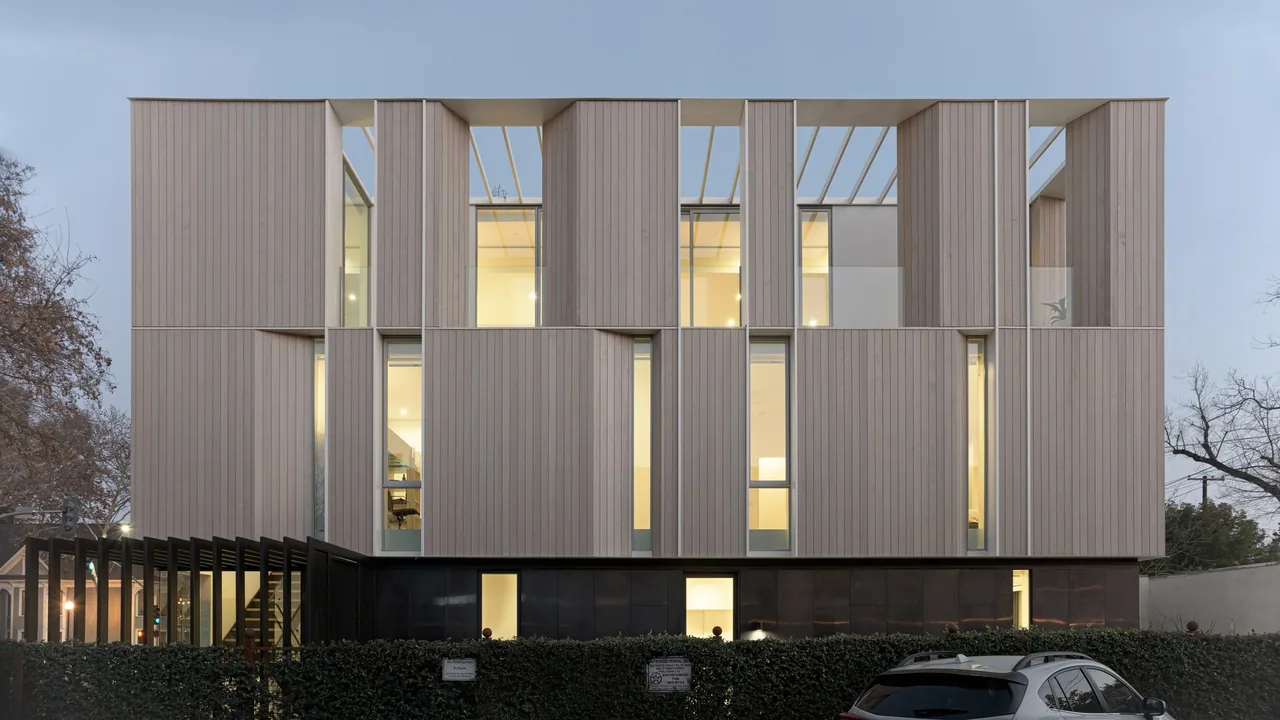 The Flex House features vertical wood siding with tall recessed windows and an open second-floor space under a pergola.