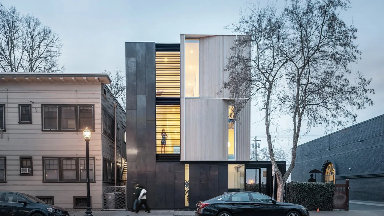 Flex house by Johnsen Schmaling Architects features a modern facade with wood panels and dark metal cladding.