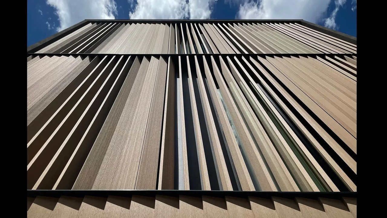 Vertical wood slats form a modern exterior screen on the curtain house facade.