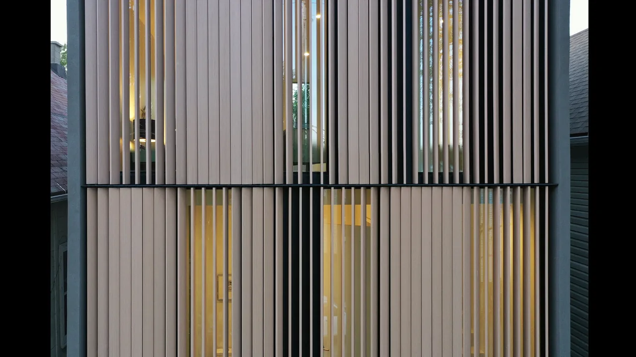 The building facade features vertical wooden slats screening narrow windows, creating a rhythmic pattern while allowing glimpses inside.