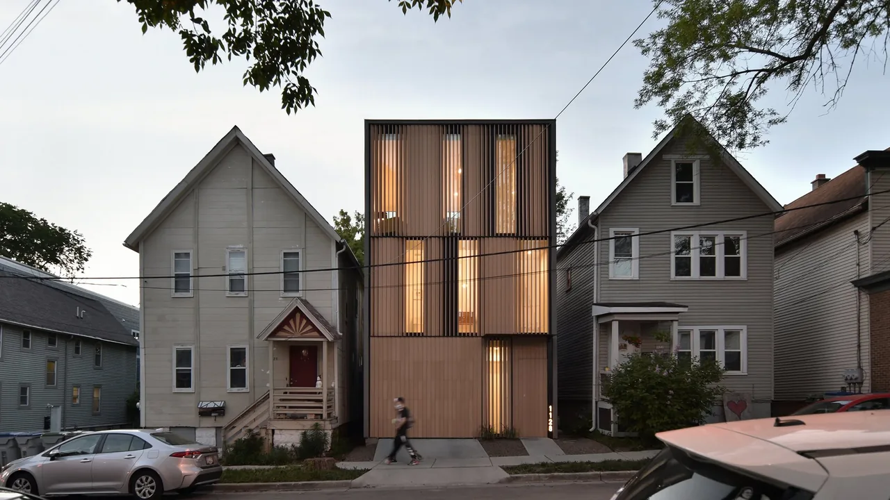 The Curtain House features a vertical wooden slat facade and narrow windows, contrasting with neighboring traditional houses.