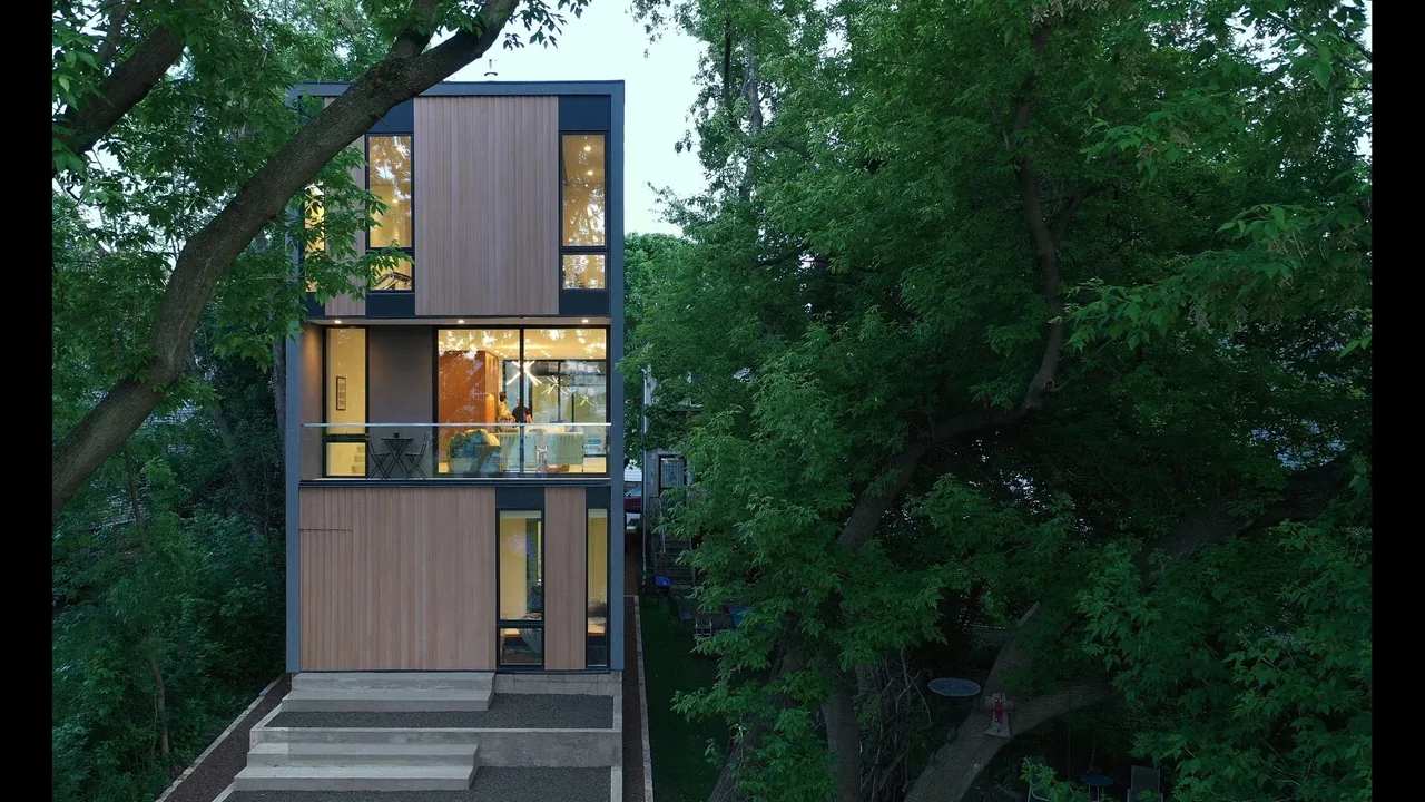 The Curtain House features narrow windows and vertical wood paneling in an urban setting surrounded by mature trees.