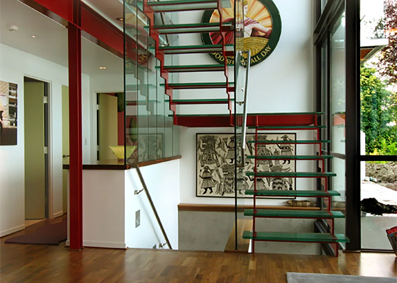 Modern stairwell with glass steps and red steel beams in the Bainbridge Island Guest Residence.