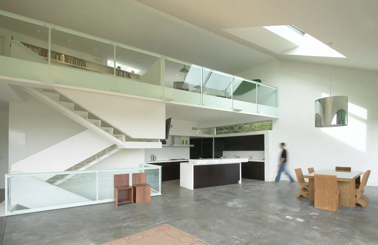 Open-plan kitchen and dining area with skylight and glass balcony railing at Hill House.