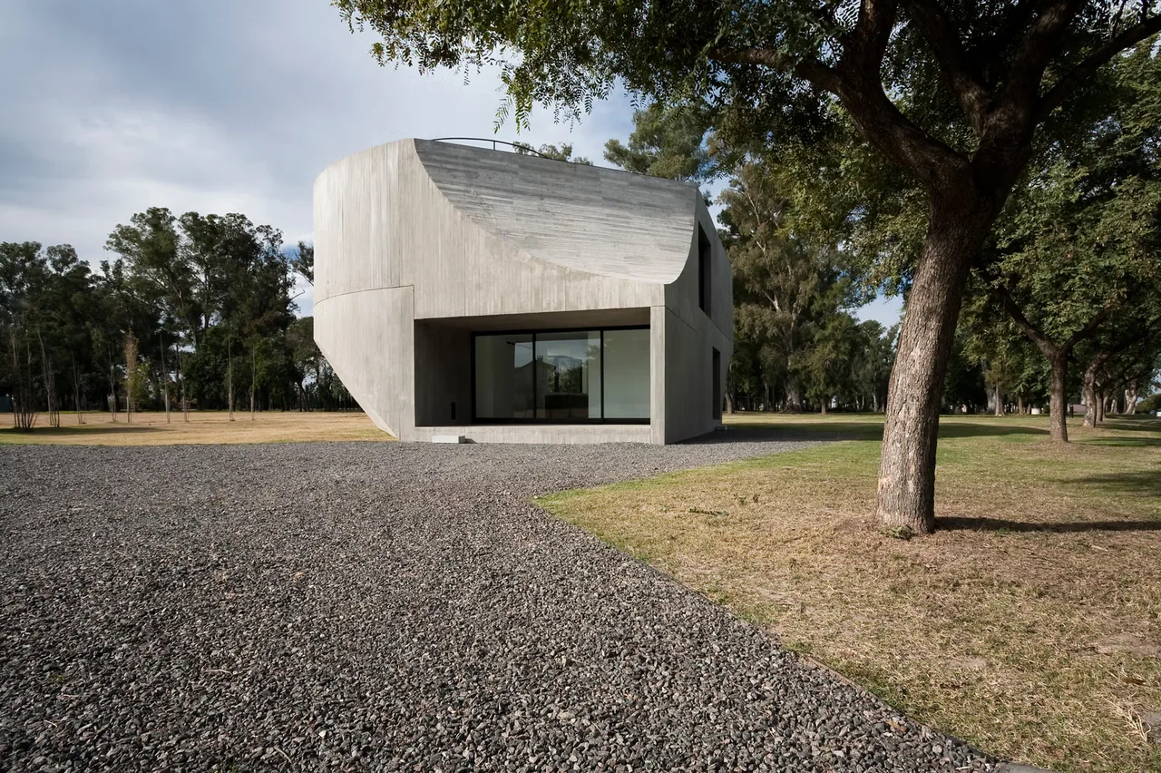 View House features a curved concrete facade with large glazing and black window frames in a minimal landscape.