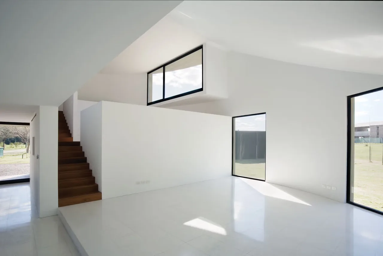 Modern interior featuring black window frames, a wooden staircase, and white walls with large glazing.