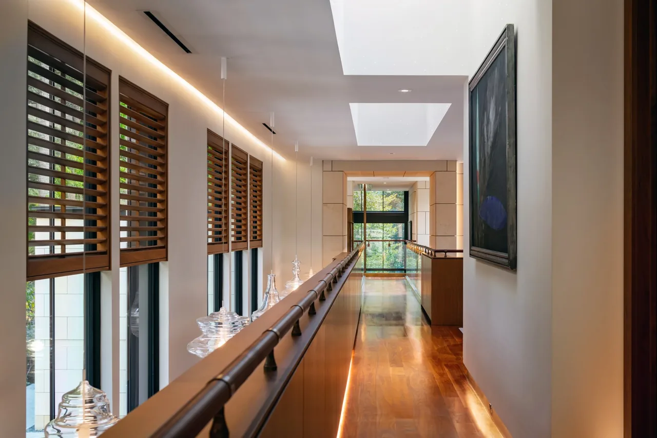 Bright hallway with parquet wood floor, skylights, and wood blinds along the windows.