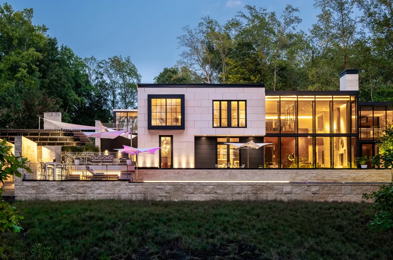 Villa Virginia features large windows, a landscaped courtyard, and outdoor seating on a stone terrace with lighting.