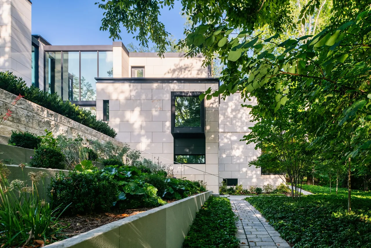Modern home with stone cladding and large reflective glass windows amidst green landscaping at Villa Virginia.