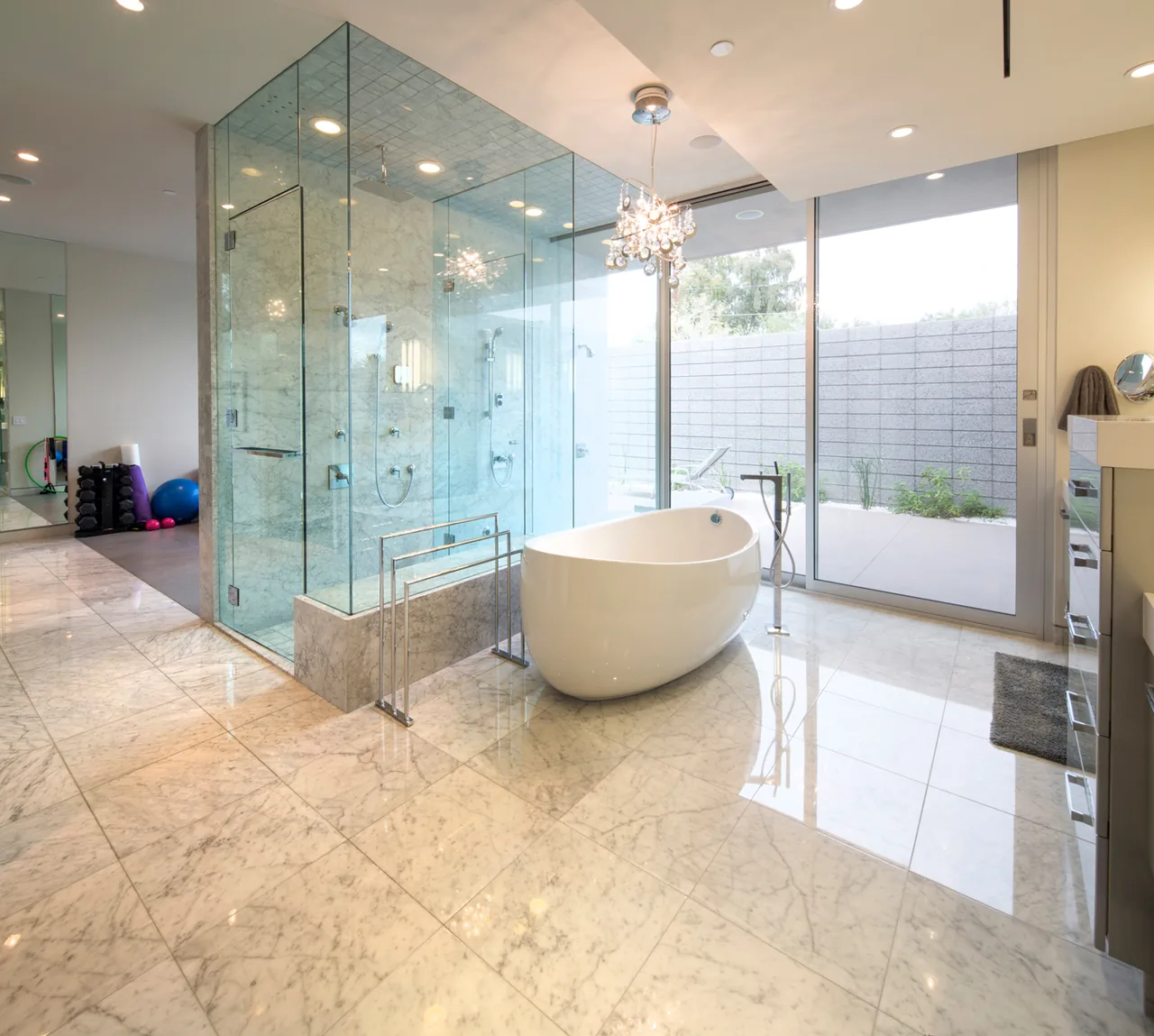 Birds Nest Residence bathroom featuring a freestanding tub and glass shower with polished marble floors and large sliding door to patio.