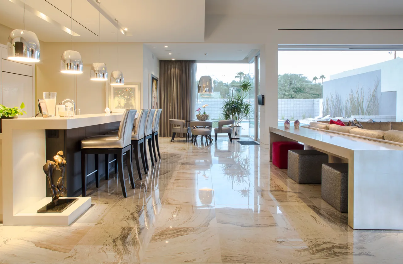Birds Nest Residence interior showing open kitchen with breakfast bar, dining area, and living space with access to outdoor patio.
