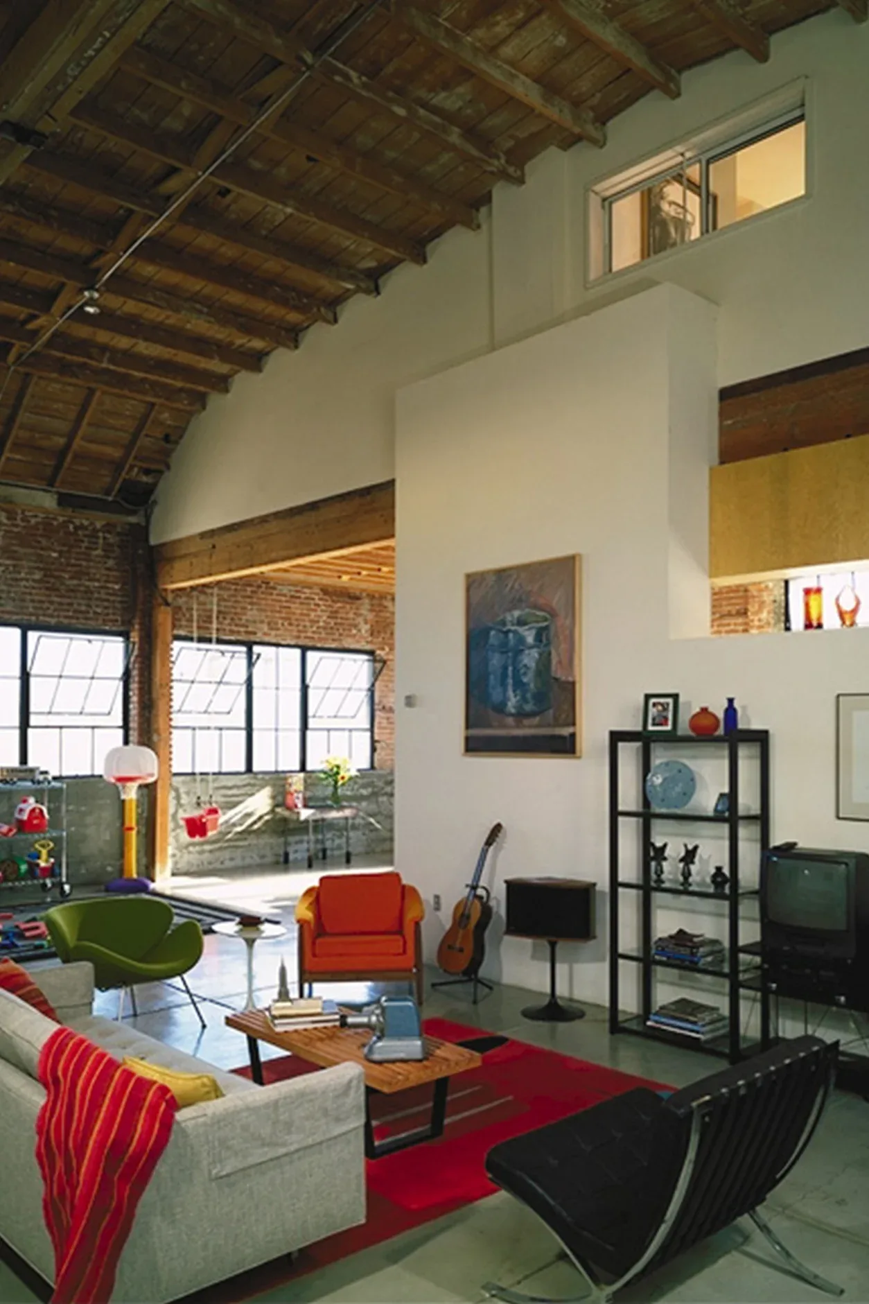 Living area of Waltmon Lofts with exposed beams, brick walls, and mid-century modern style furniture by Kevin deFreitas Architects.