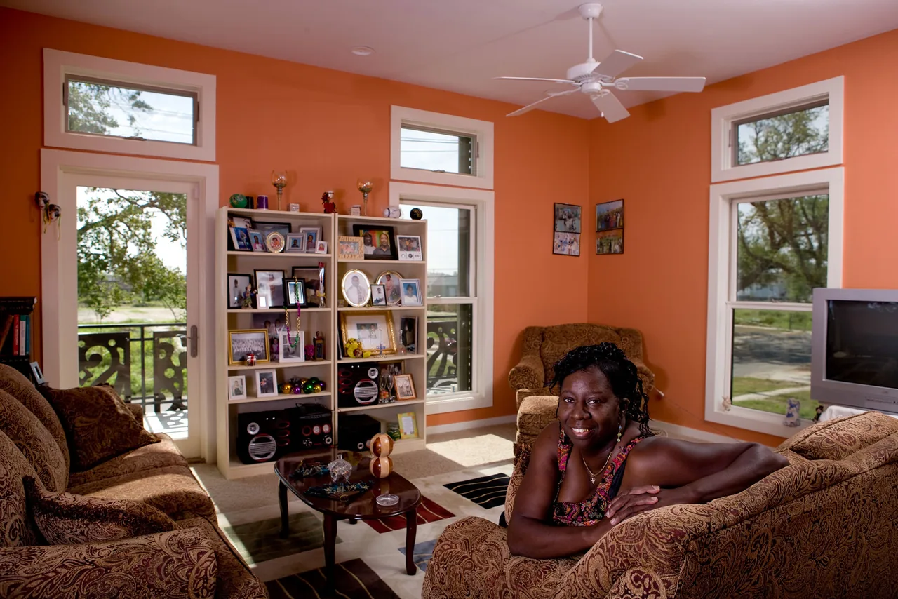The living room features orange walls, large windows with decorative metal railings visible outside, and patterned upholstered furniture.