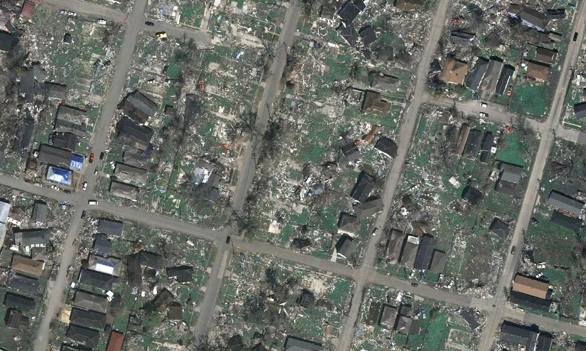 Aerial photo showing widespread residential damage with many homes partially destroyed and debris covering the area.
