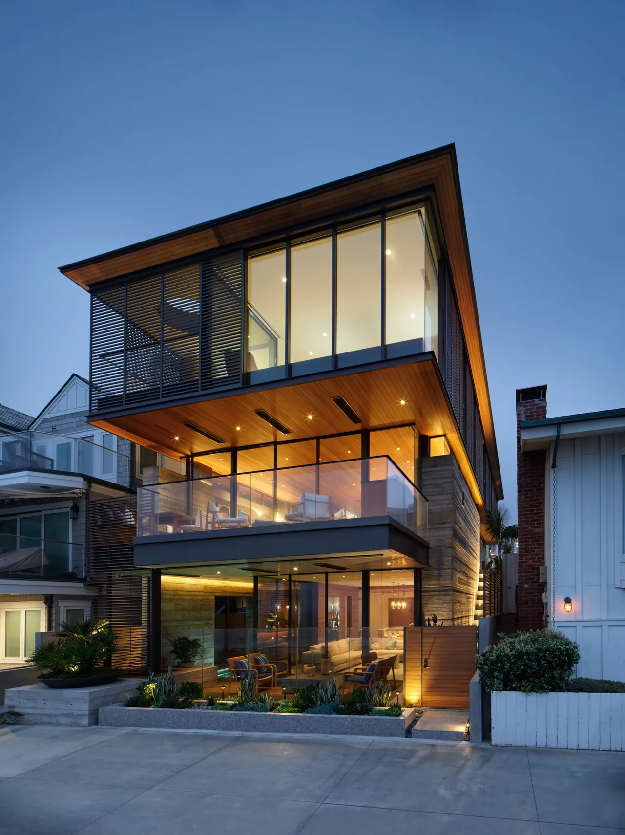 The Vessel is a modern three-story house with large glass walls, wood ceilings and siding, and ambient outdoor lighting.